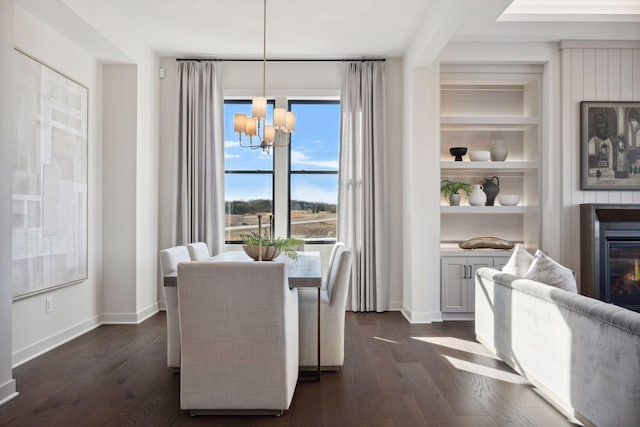 dining space with dark wood-style floors, baseboards, built in shelves, and a chandelier