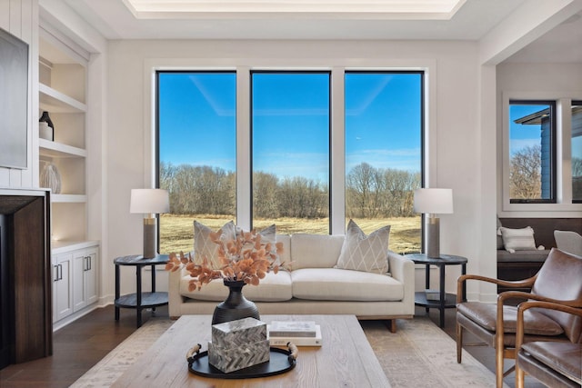 living room featuring built in features, a wealth of natural light, and dark wood-style flooring