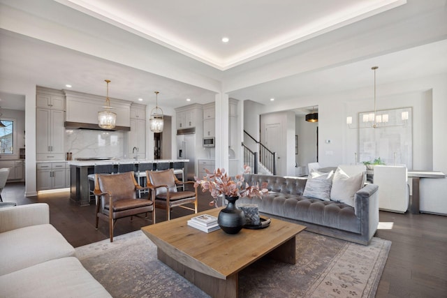 living area featuring a chandelier, dark wood-type flooring, stairway, and recessed lighting