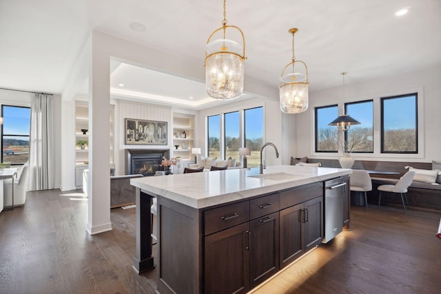 kitchen featuring hanging light fixtures, dark wood-type flooring, open floor plan, a sink, and dark brown cabinets