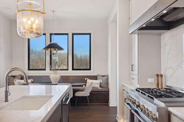 kitchen with stainless steel appliances, premium range hood, a sink, hanging light fixtures, and breakfast area