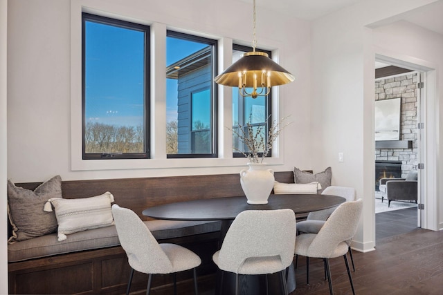 dining room featuring dark wood-style floors, breakfast area, a fireplace, and a notable chandelier