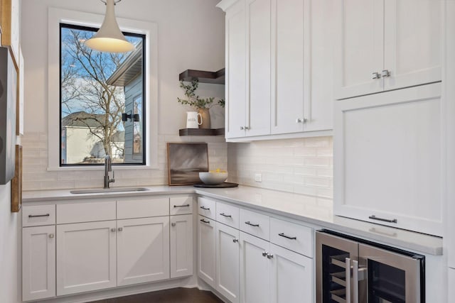 kitchen with wine cooler, white cabinetry, light countertops, open shelves, and decorative light fixtures