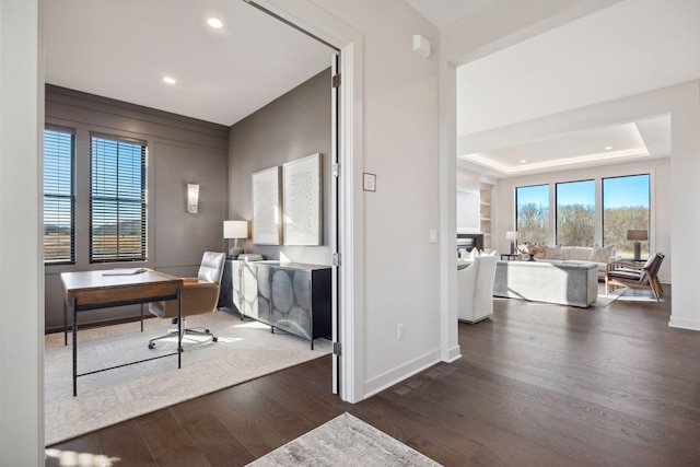 office space featuring recessed lighting, dark wood-style flooring, a raised ceiling, and baseboards