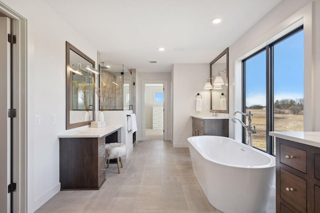 full bath with baseboards, a freestanding bath, vanity, a shower stall, and recessed lighting