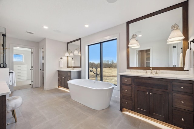 full bath with a walk in closet, a soaking tub, visible vents, a sink, and plenty of natural light