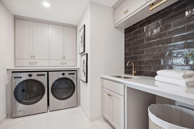 laundry room with light tile patterned floors, cabinet space, a sink, independent washer and dryer, and baseboards