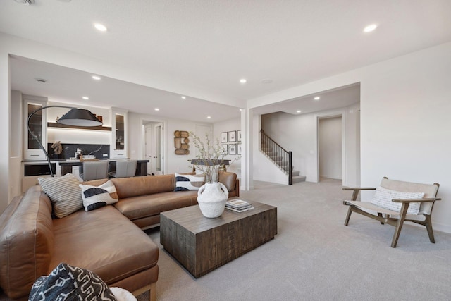 living area featuring recessed lighting, light carpet, and stairway