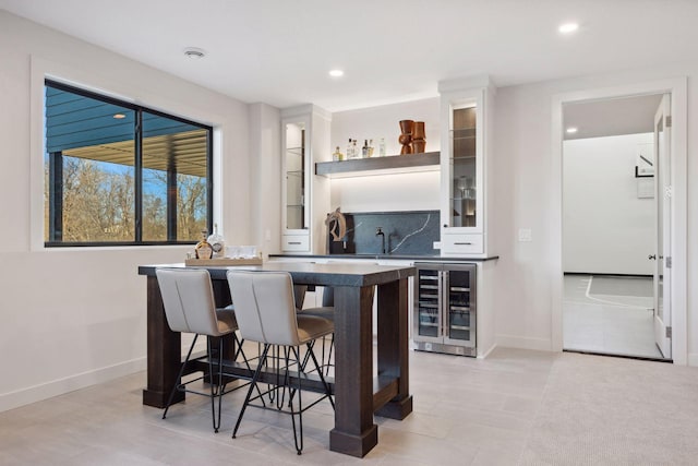 bar with wine cooler, indoor wet bar, backsplash, and baseboards