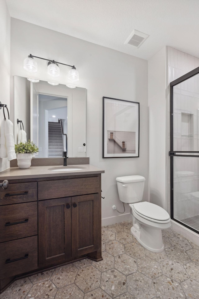 full bath featuring toilet, visible vents, vanity, baseboards, and a shower stall