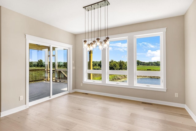 unfurnished dining area featuring light hardwood / wood-style floors and a notable chandelier