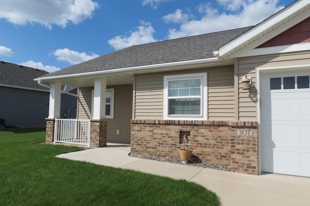 view of exterior entry featuring a porch, a garage, and a lawn