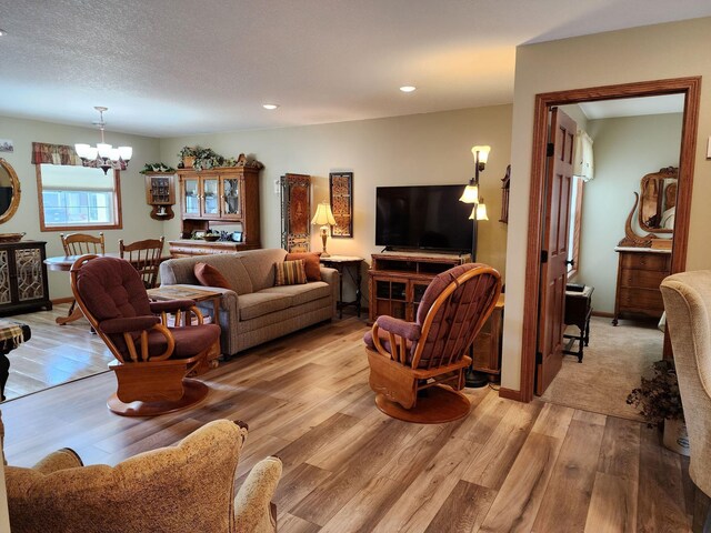 living room with an inviting chandelier, a textured ceiling, and light hardwood / wood-style floors