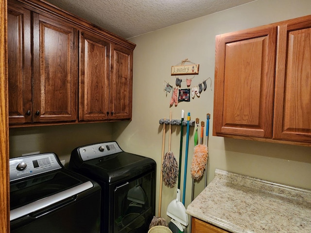 laundry room featuring cabinets, a textured ceiling, and washing machine and clothes dryer