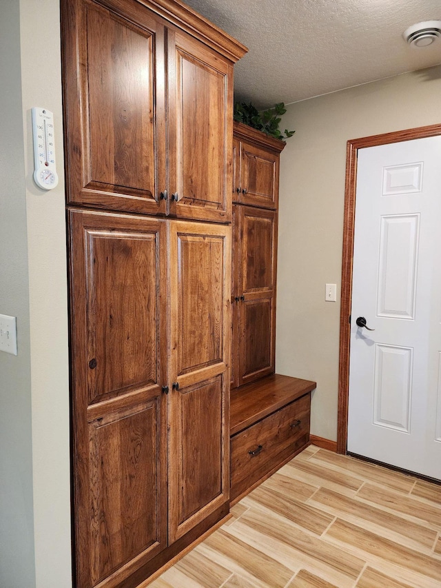 mudroom featuring a textured ceiling and light hardwood / wood-style flooring