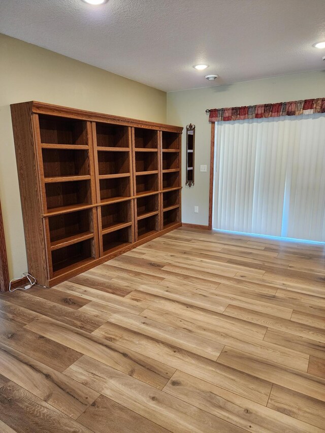 empty room with light hardwood / wood-style floors and a textured ceiling