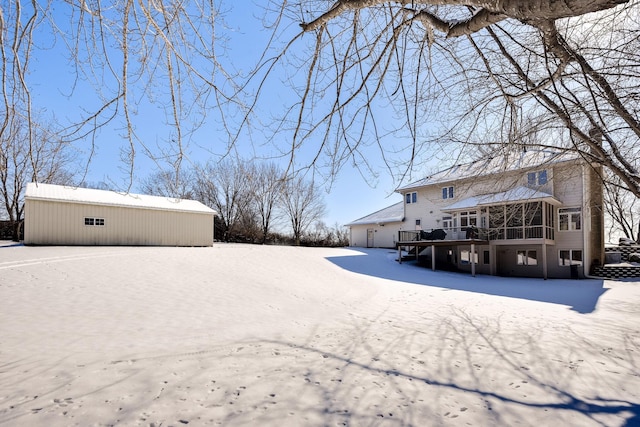 yard covered in snow with a sunroom, a deck, and an outdoor structure