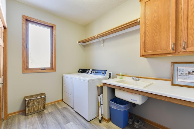 washroom featuring separate washer and dryer, light hardwood / wood-style flooring, and cabinets