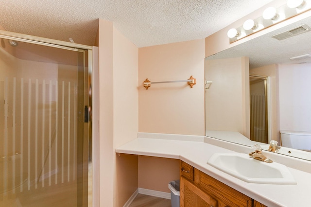 bathroom with vanity, a shower with shower door, and a textured ceiling