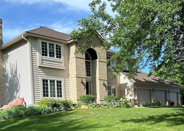 traditional-style house featuring an attached garage, brick siding, roof with shingles, and a front yard