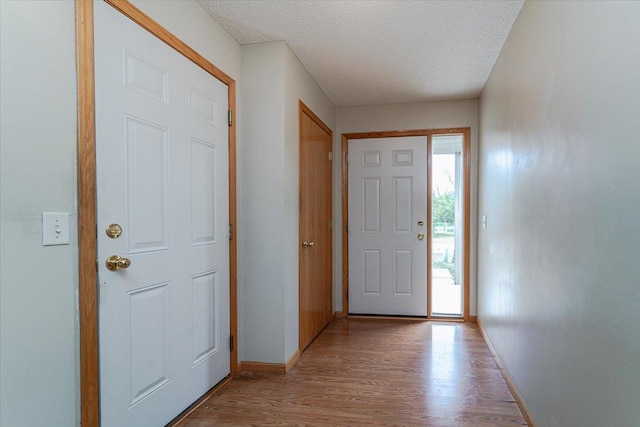 doorway to outside with a textured ceiling and light wood-type flooring