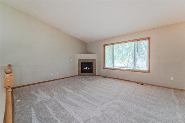 unfurnished living room with a fireplace, light colored carpet, and lofted ceiling