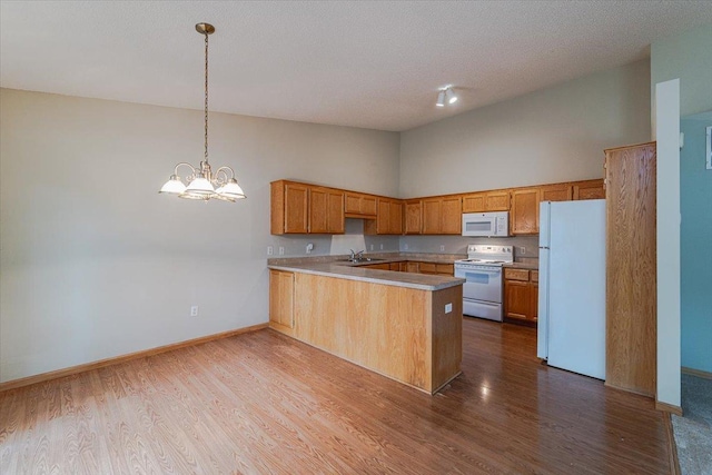 kitchen featuring sink, hanging light fixtures, high vaulted ceiling, kitchen peninsula, and white appliances