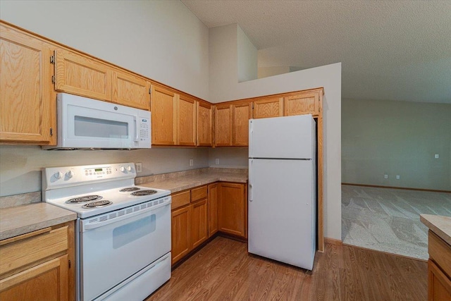 kitchen with a textured ceiling, light hardwood / wood-style flooring, high vaulted ceiling, and white appliances