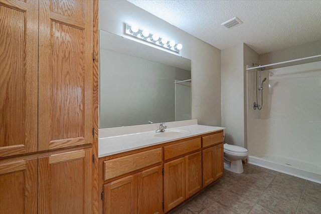 bathroom with vanity, a textured ceiling, toilet, and walk in shower