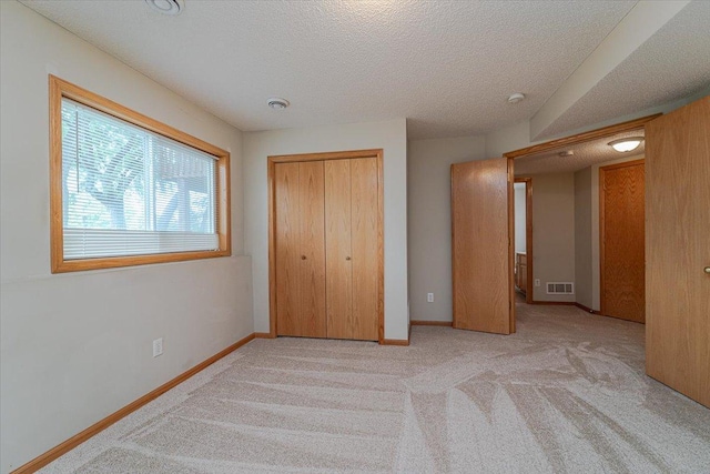 unfurnished bedroom featuring light carpet, a closet, and a textured ceiling