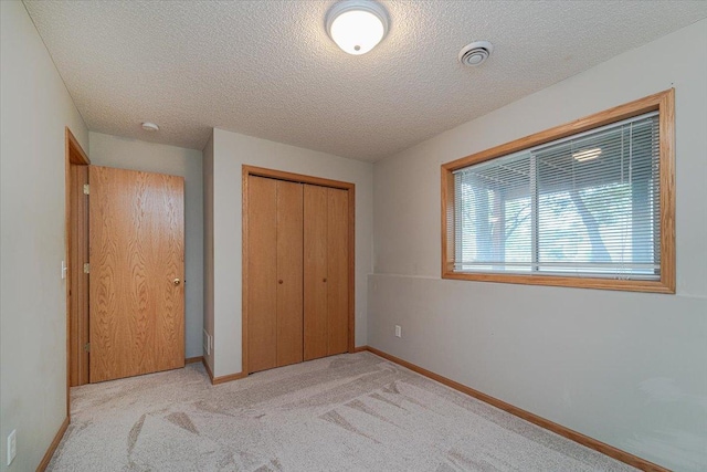 unfurnished bedroom with light carpet, a textured ceiling, and a closet