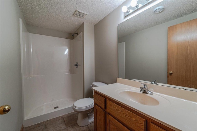 bathroom featuring vanity, a shower, tile patterned floors, toilet, and a textured ceiling