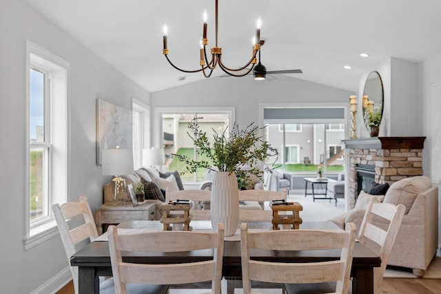 dining room featuring a fireplace, lofted ceiling, light hardwood / wood-style flooring, and ceiling fan with notable chandelier