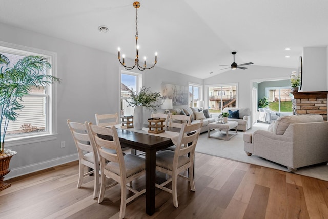 dining space featuring lofted ceiling, ceiling fan with notable chandelier, and light hardwood / wood-style flooring