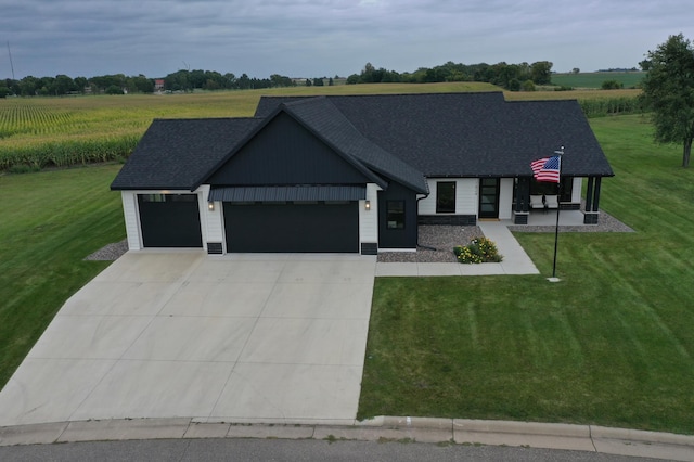 modern farmhouse featuring a front yard, a rural view, and a garage