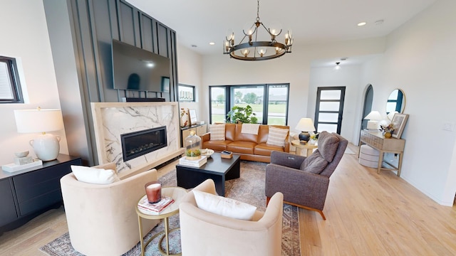 living room featuring a notable chandelier, a premium fireplace, and light hardwood / wood-style floors