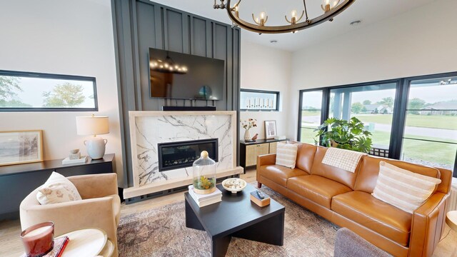 living room featuring wood-type flooring, a chandelier, and a premium fireplace