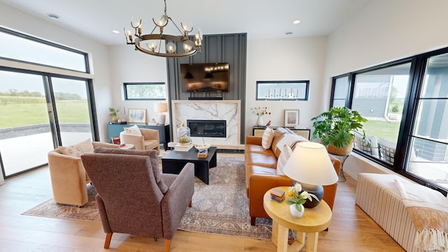 living room with light hardwood / wood-style floors, an inviting chandelier, a high end fireplace, and radiator heating unit