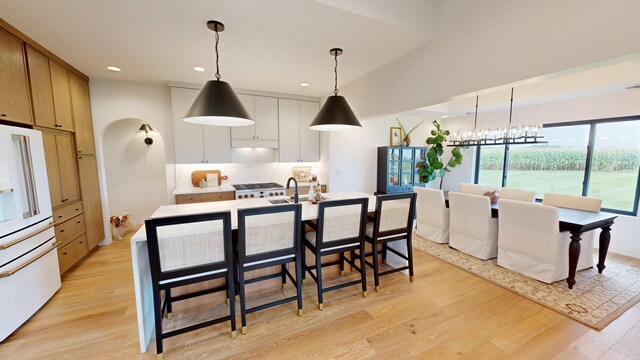 kitchen with white refrigerator, decorative light fixtures, light hardwood / wood-style floors, and white cabinetry