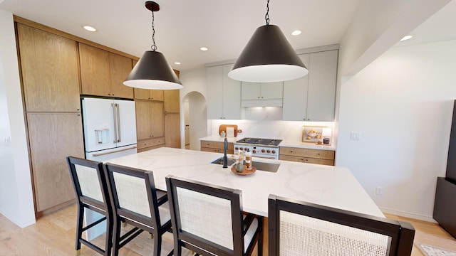 kitchen featuring white cabinets, high quality appliances, light hardwood / wood-style flooring, and decorative light fixtures