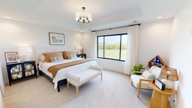 bedroom featuring light colored carpet, an inviting chandelier, and a tray ceiling