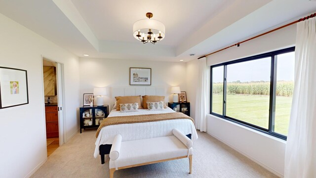 carpeted bedroom featuring multiple windows, a tray ceiling, and an inviting chandelier