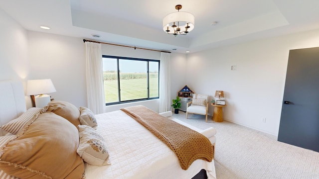 carpeted bedroom featuring a raised ceiling and a chandelier