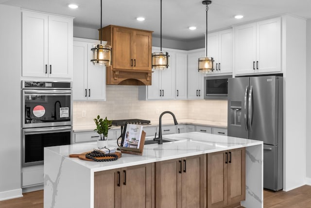 kitchen featuring appliances with stainless steel finishes, wood-type flooring, an island with sink, and white cabinets