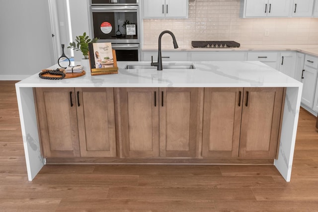 kitchen featuring light wood-type flooring, a sink, and backsplash