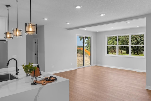 living area with light wood finished floors, baseboards, a textured ceiling, and recessed lighting