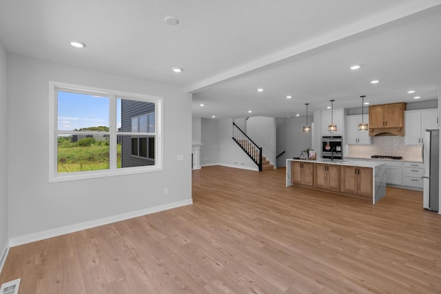 kitchen with visible vents, decorative backsplash, light wood-style flooring, open floor plan, and stainless steel appliances