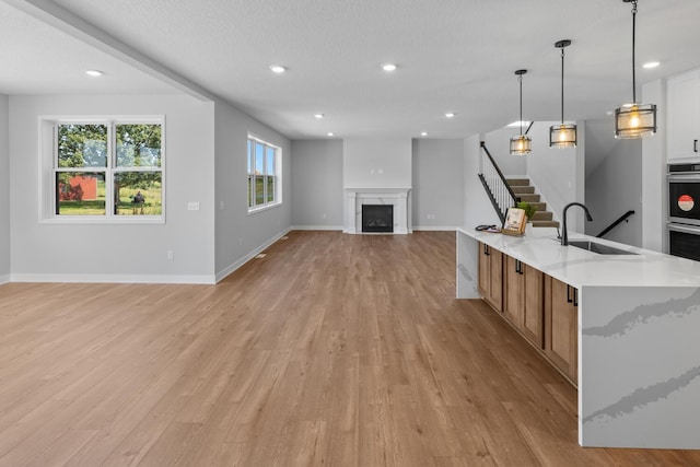 kitchen with open floor plan, a fireplace, a sink, and light wood-style flooring