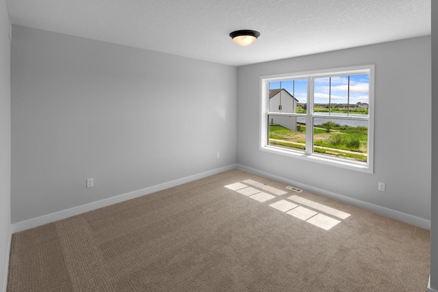 unfurnished room with a textured ceiling, carpet, visible vents, and baseboards