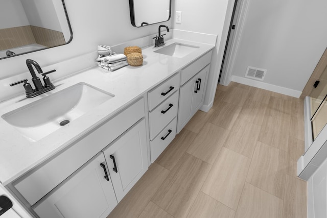 full bathroom featuring double vanity, walk in shower, a sink, and visible vents